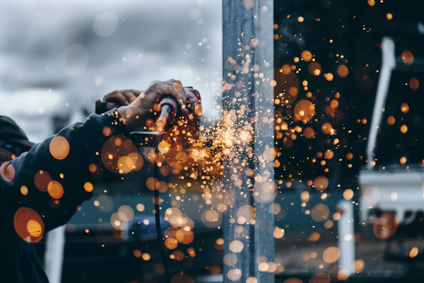 A skilled tradesperson shaping metal, with sparks flying from the tool